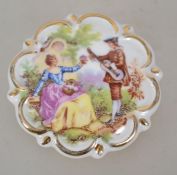 A 1970s ceramic brooch in the Fragonard style having a central image with gilt border and a loop