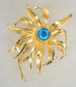 A large gold tone Alana Stewart flower brooch with central set blue rhinestone with roller clip