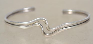 A sterling silver bangle bracelet of crossover form. Rubbed hallmarks. Weighs grams measures 6.