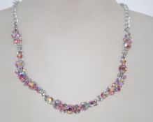 A vintage pink aurora rhinestone necklace in a silver tone setting with an adjustable hook