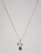 A vintage silver pendant on chain in the form of a flower set with a garnet stone with gold washed