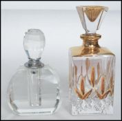 Two vintage 20th century art deco cut glass perfume bottles of faceted form with stoppers atop.
