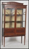 An early 20th century Edwardian marquetry inlaid twin astragal glass door display cabinet raised