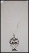 An unusual silver luck owl pendant with garnet eyes being set to a silver necklace chain, complete