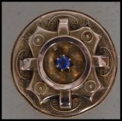 A Victorian 9ct gold locket brooch set a central blue stone within raised etched setting having  c