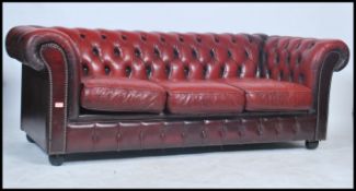 A ox blood leather low back three - seater Chesterfield sofa, with deep button back and sides,