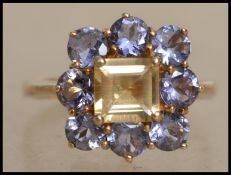 A hallmarked 9ct gold cluster ring set with a central square cut citrine surrounded by a halo of