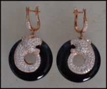 A pair of ladies contemporary silver and onyx panther earrings having emerald eyes. The onyx of