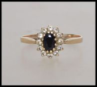 A hallmarked 9ct gold ring with central oval cut sapphire surrounded by a CZ halo . Hallmarked