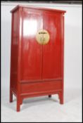 A Chinese large 20th century red lacquered marriage cupboard wardrobe. The large cabinet with turned