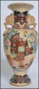 A large Japanese stoneware Satsuma vase being decorated with scenes of merchantmen. Twin handles