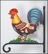 A vintage style cast wall hanging cockerel having a rococo style angular wall bracket pierce