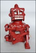 A vintage style cast iron Robert The Robot 1950 money bank in red being stamped Hubles to base.