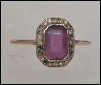 An Edwardian 9ct gold and amethyst ring with cushion cut amethyst surrounded by a halo of