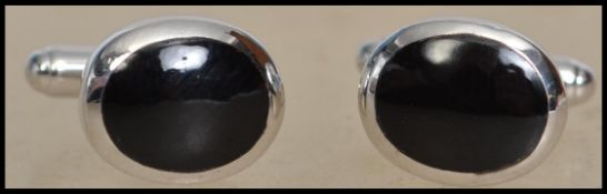 A pair of contemporary gentlemans silver cufflinks with onyx black roundel panels and swivel bar