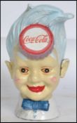 A vintage style, 20th century cast iron Coca Cola money bank of a young boys head having Coca Cola