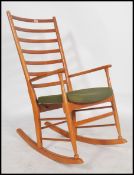 A 1960's Danish inspired teak ladder back rocking chair in the manner of Scandart having a green