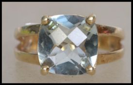 A hallmarked 9ct gold ring set with a faceted green blue stone having split styled shoulders.