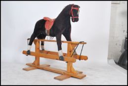 A large 20th century rocking horse being well upholstered with saddle and reins being set over a
