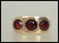 A heavy 9ct gold ring set with three round cut garnets. Marked 9ct tests 9ct gold.  Weight 10g. Size