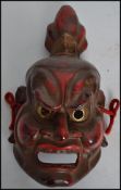 An early 20th century Japanese Kabuki / Noh theatre mask being handpainted in brown and red paints
