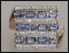 A hallmarked 9ct gold ring set with oval sapphires and illusion set diamonds in a geometric pattern.