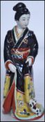 An early 20th century Oriental ceramic porcelain figurine of a Japanese Geisha Girl being hand