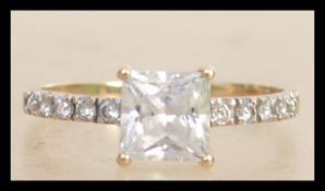 A 9ct gold ring set with a central princess cut CZ