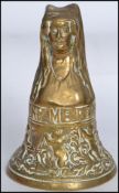 A sixteenth century style cast bronze hand bell formed as a nun, decorated in relief with a