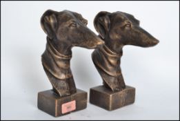A pair of vintage style cast iron busts of grey hound dogs raised on plinth bases having a bronze