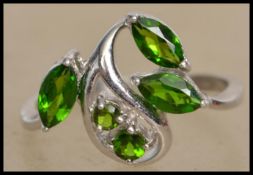 A hallmarked 9ct white gold ring set with green stones in the Art Nouveau style. Hallmarked