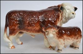 A large vintage 20th century ceramic Hereford Bull standing in usual pose together with another.