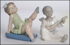 A Llladro figurine of a child angel playing the mandolin together with another Lladro figurine of