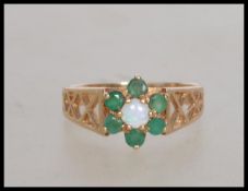 A hallmarked 9ct gold ring set with  a central opal stone surrounded by an emerald halo.