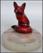 An early 20th century Royal Doulton ceramic flambe fox in a seated position in the famous flambe red
