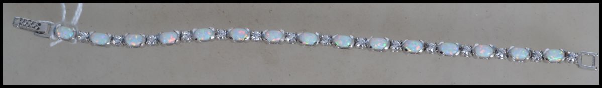 A beautiful ladies silver and opal adorned tennis bracelet with filigree type clip clasp. Measures