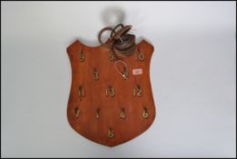 A vintage 20th century wall mounted hoopla game, the metal hooks mounted on a wooden armorial shield
