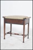 An Edwardian mahogany piano stool having a pierced h-frame stretcher under a hinged top seat with