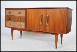 A vintage 20th century sideboard having a series of drawers and cupboards raised on shaped tapered