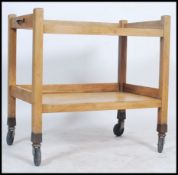 A vintage 20th century wooden bakers two tier trolley raised on metal castors with metal pull