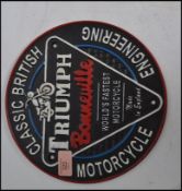 A vintage style advertising point of sale motoring plaque sign for Triumph Motorcycles of circular