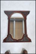 A Victorian Art Nouveau carved wall mirror of shaped form with rococo wooden carved embellishments
