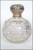A silver hallmarked ladies perfume bottle having globular cut glass body with rococo silver top