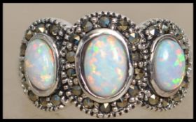 A silver ladies Art Deco style 3 stone opal ring. Each stone of cabochon form having marcasite
