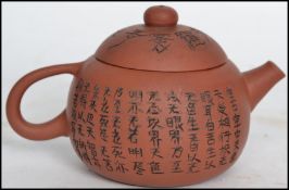 A terracotta Yixing teapot of squat globular form having incised character marks all around the