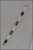 A 9ct gold bracelet with black and mother of pearl links with oriental script. Marked 375 9ct  tests