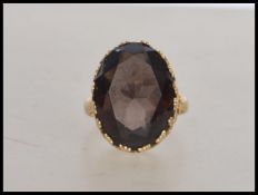 A hallmarked 9ct gold ring set with  a large oval cut brown stone with pierced lattice work