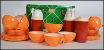 A retro mid century picnic set being set within a pressed tin case with tartan decoration, having an