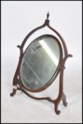 A vintage early 20th century mahogany toilet swing mirror of oval form set in a pierced bell shape