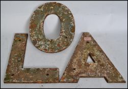A set of 3 large early 20th century cast iron shop external advertising sign letters being dug up